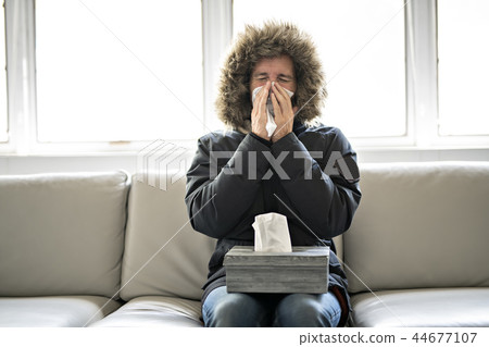 Man have flu on the sofa at home with winter coat Man have flu on the sofa at home with winter coat 44677107