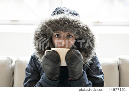 Woman have cold drink coffee on the sofa at home with winter coat 44677161