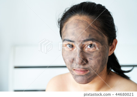 asia woman applied charcoal mask on her bare face 44680021
