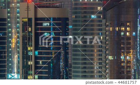 Window of the multi-storey skyscrapers of glass and steel office lighting and people within timelapse 44681757