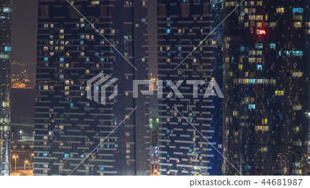 Window of the multi-storey skyscrapers of glass and steel office lighting and people within timelapse 44681987