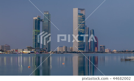 Abu Dhabi city skyline with skyscrapers before sunrise with water reflection night to day timelapse Abu Dhabi city skyline with skyscrapers before sunrise with water reflection night to day timelapse 44682002