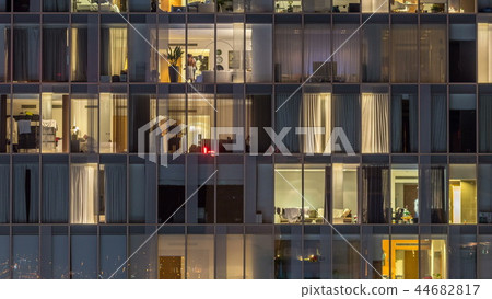 Windows of the multi-storey building of glass and steel lighting inside and moving people within timelapse Windows of the multi-storey building of glass and steel lighting inside and moving people within timelapse 44682817