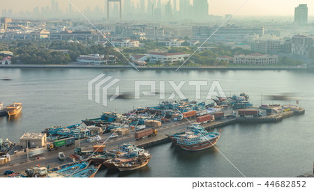 Dubai creek landscape timelapse with boats and ship in port and modern buildings in the background during sunset Dubai creek landscape timelapse with boats and ship in port and modern buildings in the background during sunset 44682852