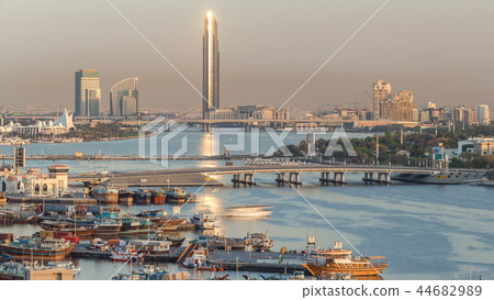 Dubai creek landscape timelapse with boats and ship in port and modern buildings in the background during sunset Dubai creek landscape timelapse with boats and ship in port and modern buildings in the background during sunset 44682989