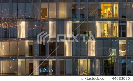 Windows of the multi-storey building of glass and steel lighting inside and moving people within timelapse Windows of the multi-storey building of glass and steel lighting inside and moving people within timelapse 44683050