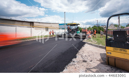 A paver finisher, asphalt finisher or paving machine placing a layer of asphalt during a repaving construction project timelapse A paver finisher, asphalt finisher or paving machine placing a layer of asphalt during a repaving construction project timelapse 44683091