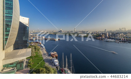 Dubai creek landscape timelapse with boats and ship in port and modern buildings in the background during sunset Dubai creek landscape timelapse with boats and ship in port and modern buildings in the background during sunset 44683214