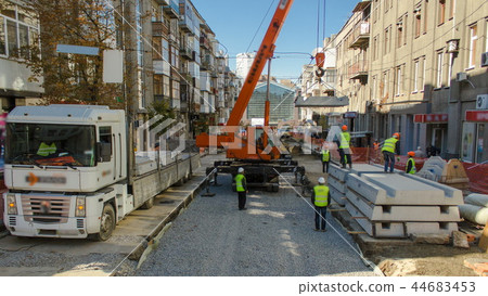 Unloading concrete plates from truck by crane at road construction site timelapse. 44683453