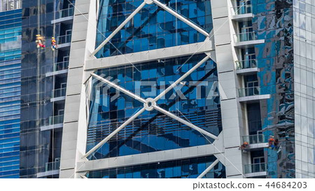 Washers wash the windows of modern skyscraper in Dubai timelapse 44684203