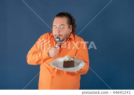 Funny fat man in orange shirt with a piece of chocolate cake on a plate Funny fat man in orange shirt with a piece of chocolate cake on a plate 44691241