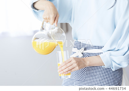 A woman pouring juice into a glass A woman pouring juice into a glass 44691734
