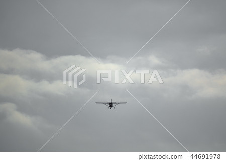 Light aircraft flying over cloudy sky background 44691978