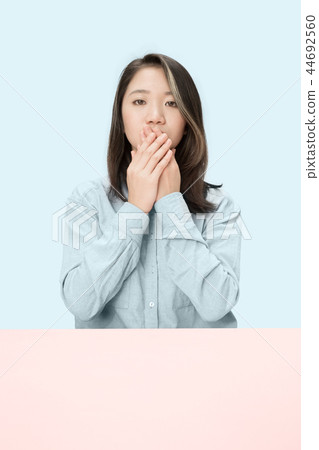 Young woman covering her mouth Young woman covering her mouth 44692560