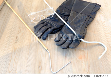 Protective gloves, goggles and a hook for working with venomous snakes on the background of natural Protective gloves, goggles and a hook for working with venomous snakes on the background of natural 44693463