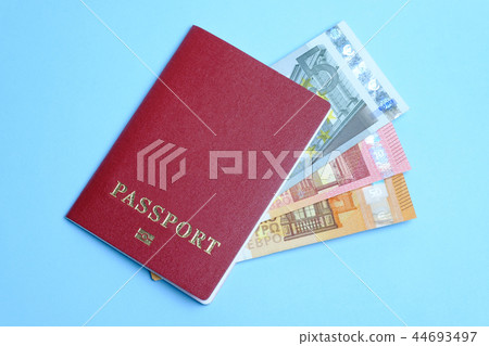 Euro banknotes invested in a foreign passport isolated on a blue background. Travel to Europe. Euro banknotes invested in a foreign passport isolated on a blue background. Travel to Europe. 44693497