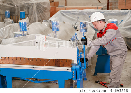 Production of ventilation and drainpipe. Worker unpacks the machine in the warehouse. Tool and 44695218