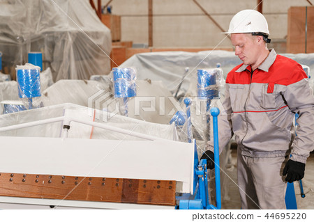 Production of ventilation and drainpipe. Worker unpacks the machine in the warehouse. Tool and 44695220