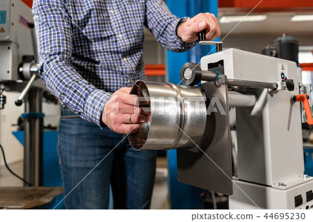 Production of ventilation and drainpipe. man work with production rolling tool, electric machine Production of ventilation and drainpipe. man work with production rolling tool, electric machine 44695230