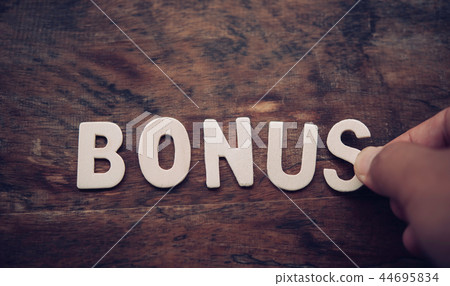 Place the word "BONUS" white on the wooden floor. Place the word "BONUS" white on the wooden floor. 44695834