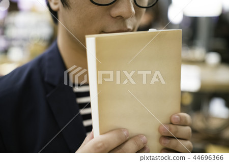 男子在一家咖啡館拿一本書 44696366
