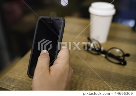 操作在咖啡館的男性手一個智能手機 操作在咖啡館的男性手一個智能手機 44696369