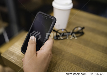 操作在咖啡館的男性手一個智能手機 操作在咖啡館的男性手一個智能手機 44696370