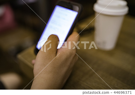 操作在咖啡館的男性手一個智能手機 操作在咖啡館的男性手一個智能手機 44696371