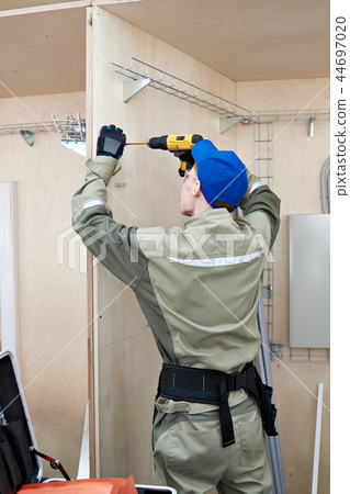 Electrician drills holes for cable routing 44697020