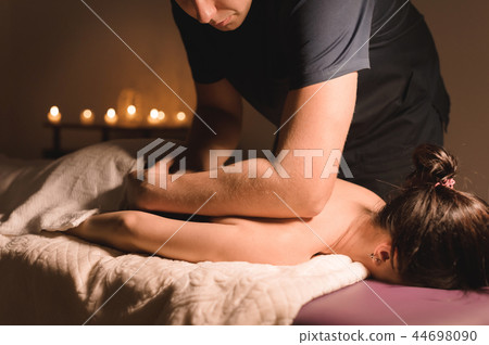 Close-up Spa massage low angle. male massage therapist doing a back and shoulder massage to a young Close-up Spa massage low angle. male massage therapist doing a back and shoulder massage to a young 44698090