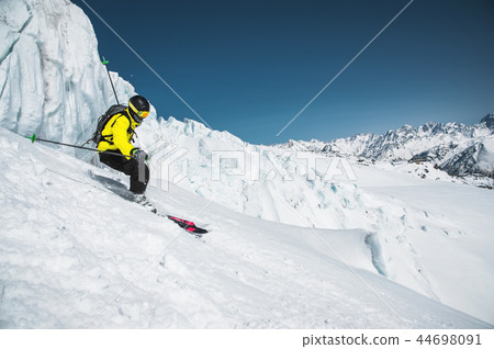 A skier at speed rides on a snowy slope freeride. The concept of winter extreme sports A skier at speed rides on a snowy slope freeride. The concept of winter extreme sports 44698091