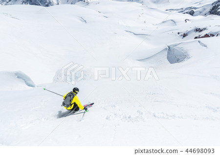 A skier at speed rides on a snowy slope freeride. The concept of winter extreme sports A skier at speed rides on a snowy slope freeride. The concept of winter extreme sports 44698093
