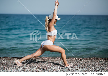 Beautiful woman is doing streching exercises on the beach 44698874