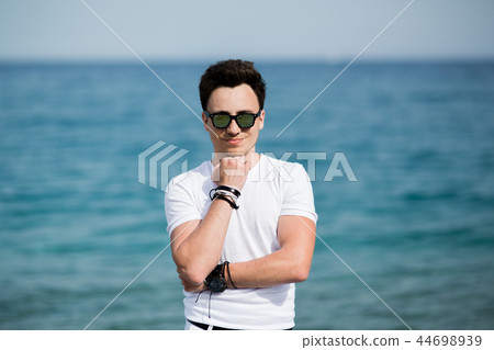 Portrait of young handsome man in sunglasses smiling on the beach 44698939