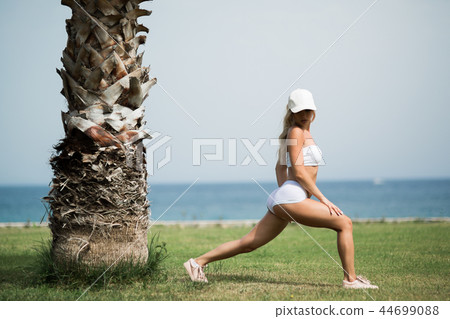 Beautiful woman is doing streching exercises on the beach Beautiful woman is doing streching exercises on the beach 44699088