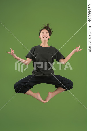 Freedom in moving. Pretty young woman jumping against green background 44699670