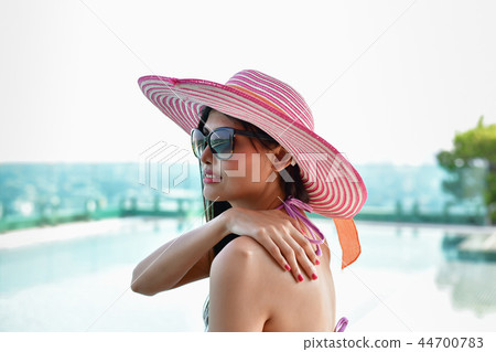 Swimsuit Concept. Beautiful girl in swimsuit is applying sunscre 44700783