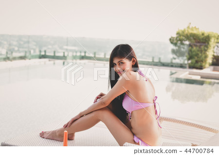Swimsuit Concept. Beautiful girl in swimsuit is applying sunscre 44700784