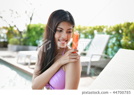 Swimsuit Concept. Beautiful girl in swimsuit is applying sunscre 44700785