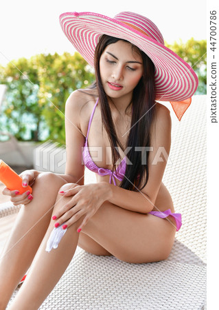 Swimsuit Concept. Beautiful girl in swimsuit is applying sunscre 44700786