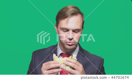 businessman eating a sandwich on a green background. quick lunch concept 44701674