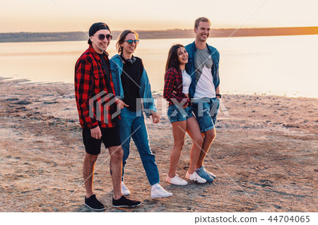 friends on beach together walking during sunset 44704065