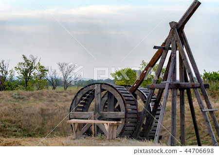 Old wooden catapult against grey sky background 44706698