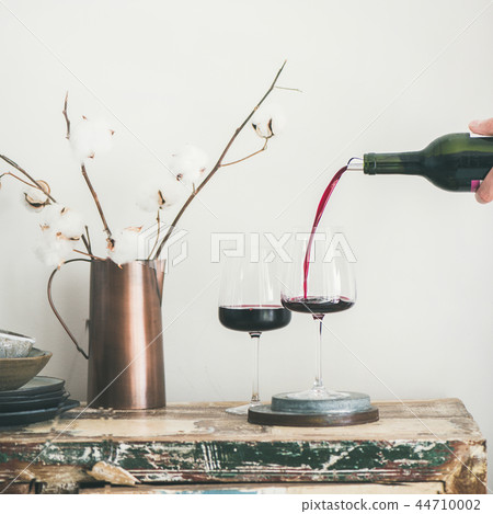 Red wine pouring from bottle in man's hand, square crop Red wine pouring from bottle in man's hand, square crop 44710002