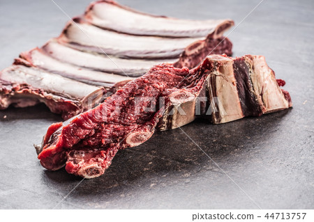 Portion of raw beef ribs on dark butcher board Portion of raw beef ribs on dark butcher board 44713757
