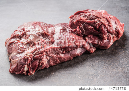 Portion of raw beef neck on dark butcher board Portion of raw beef neck on dark butcher board 44713758