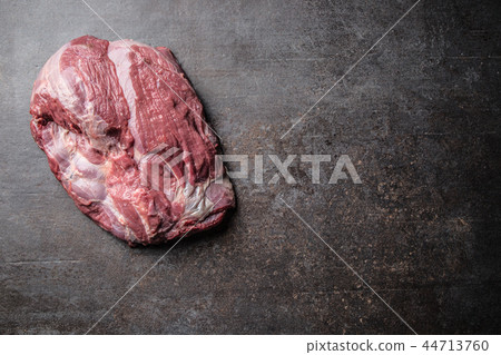 Portion of raw beef neck on dark butcher board Portion of raw beef neck on dark butcher board 44713760