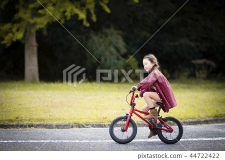 A girl riding a red bicycle A girl riding a red bicycle 44722422