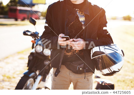 Close up view of biker's hands using his smartphone Close up view of biker's hands using his smartphone 44725605