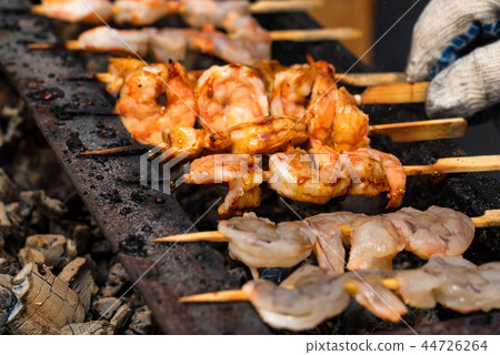 Grilled fried seafood on skewers on metal grid Grilled fried seafood on skewers on metal grid 44726264